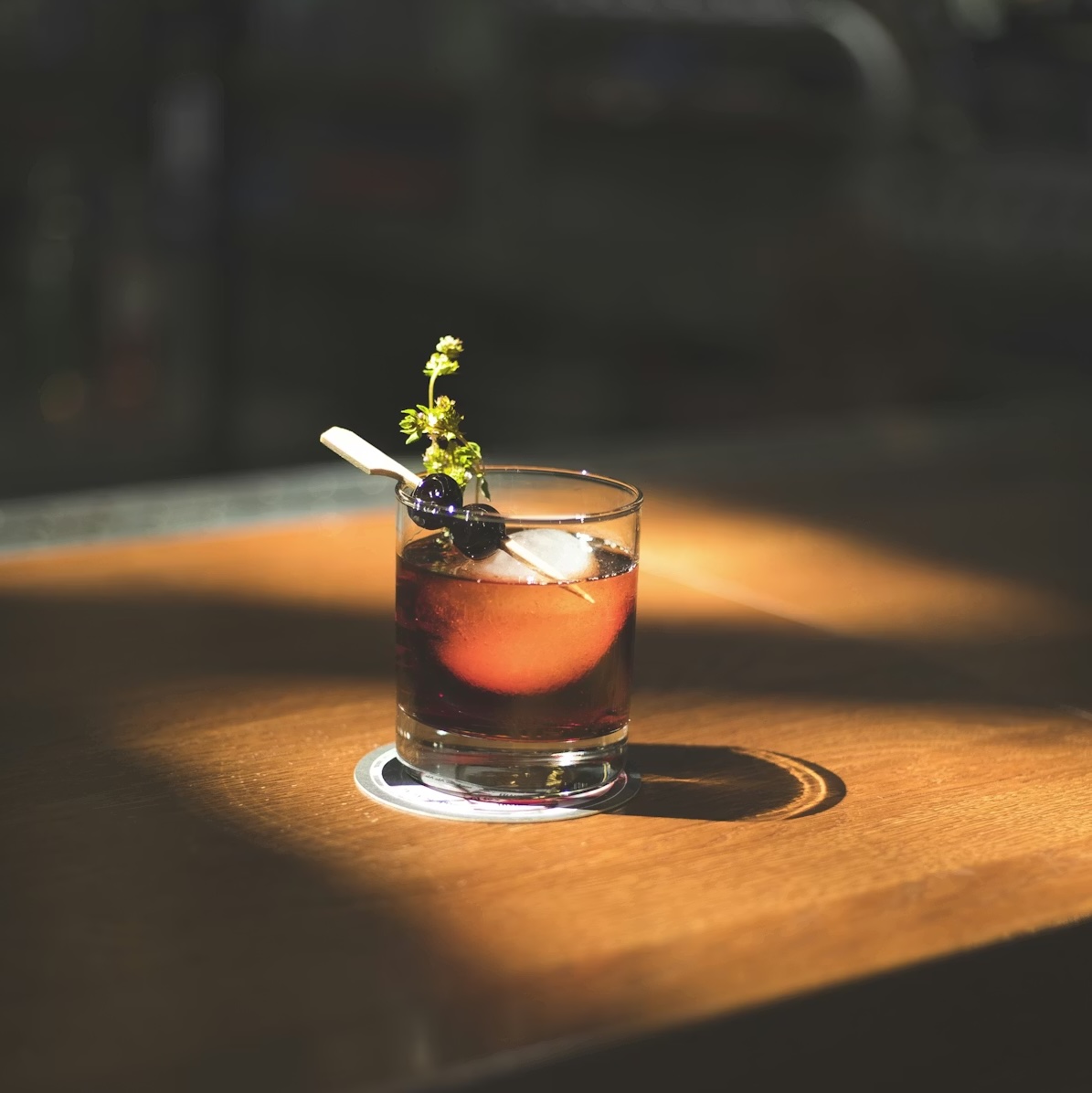 Atmospheric cocktail in a rocks glass with herb garnish — savory umami trend 2026